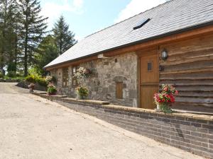 a stone building with flowers in front of it at Y Dderwen At Brynglas Farm in Llanfair Caereinion