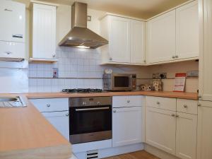 a kitchen with white cabinets and a stove top oven at Valeview Cottage in Great Malvern