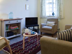 a living room with a tv and a chair and a table at Valeview Cottage in Great Malvern