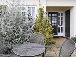 a patio with three chairs and a table at Valeview Cottage in Great Malvern