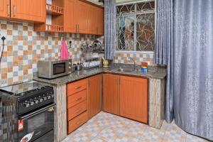 a kitchen with wooden cabinets and a microwave and a sink at Cozy 2B&B with Free Airport Pick up & Drop off in Namugongo