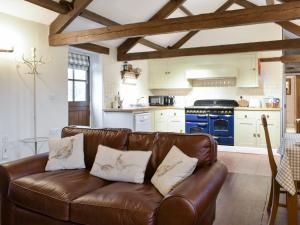 ein Wohnzimmer mit einem braunen Ledersofa in der Küche in der Unterkunft Curlew Barn in Middleham