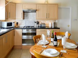 a kitchen with a wooden table with plates and wine bottles at Kirsty Cottage in Moffat