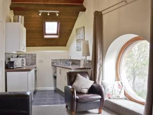 a living room with a chair and a kitchen at The Round Window in Bowness-on-Windermere