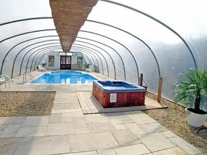 a swimming pool in a domed building next to the water at Pheasant Roost in Swanton Morley