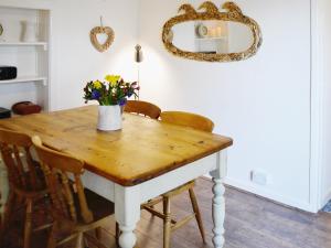 a dining room table with a vase of flowers on it at Beachside Cottage in Shaldon