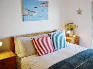 a bed with two colorful pillows on top of it at Beachside Cottage in Shaldon
