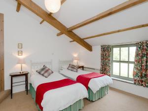 two beds in a room with white walls and wooden beams at Cowdber Barn in Cowan Bridge