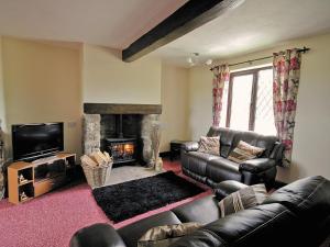 Tomfield Cottage في Kingsley: غرفة معيشة مع أريكة جلدية ومدفأة
