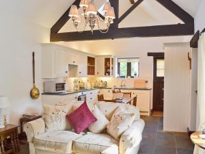 a living room with a couch and a kitchen at Paper Mill Cottage in Sutton