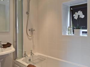 a bathroom with a shower and a tub and a sink at Paper Mill Cottage in Sutton