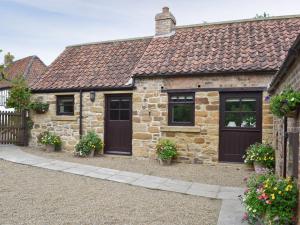 a stone house with black doors and windows at Paper Mill Cottage in Sutton