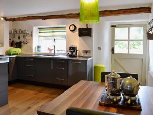 uma cozinha com uma mesa de madeira e uma bancada em Granny Mcphees Cottage Hssh em Beaworthy