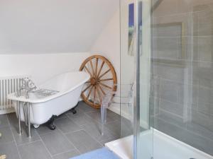 uma casa de banho com uma roda e uma banheira em Granny Mcphees Cottage Hssh em Beaworthy