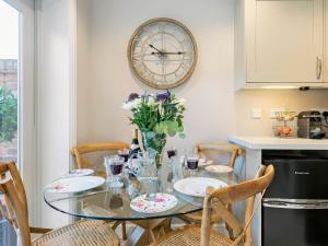 a dining room table with chairs and a clock on the wall at Pear Tree Cottage in Louth
