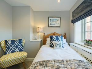 a bedroom with a bed and a chair at Pear Tree Cottage in Louth
