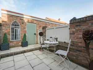 a patio with a table and chairs on a brick wall at Pear Tree Cottage in Louth