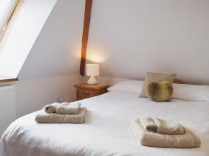 a bedroom with a white bed with towels on it at Chive - E4326 in Ludham