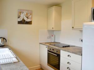 a kitchen with white cabinets and a stove top oven at Foulden Hill Farm Cottage in Foulden