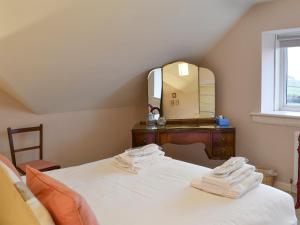 a bedroom with a bed with a dresser and a mirror at Foulden Hill Farm Cottage in Foulden