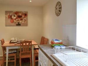a kitchen with a table and a clock on the wall at Foulden Hill Farm Cottage in Foulden