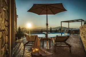 a pool with an umbrella and two chairs and a table with at Violet Private Stone Villa in Lagópodhon