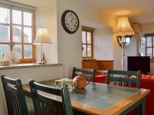 a dining room with a table and a clock on the wall at Cruck Cottage in Sinnington