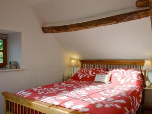 a bedroom with a red bed with a book on it at Cruck Cottage in Sinnington