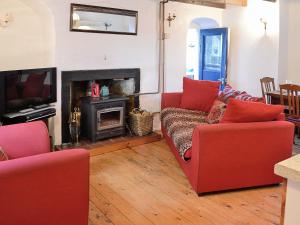 sala de estar con 2 sofás rojos y chimenea en The Cottage en Saint Cyrus