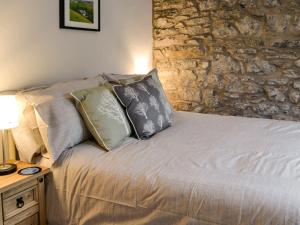 a bedroom with a bed with pillows and a stone wall at Miller Cottage in Malham