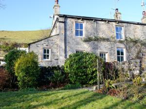 an old stone house with a green yard at Miller Cottage in Malham
