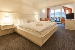 a bedroom with a large white bed with a large window at Hotel Magdalenenhof inklusive MeineCardPlus in Willingen