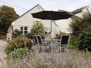 a table and chairs with an umbrella in a garden at Stable Cottage - Hw7452 in Whitford