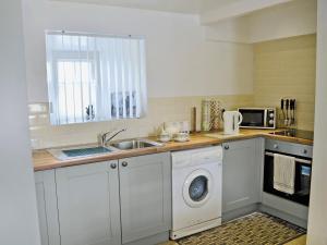 een keuken met een wasmachine en een wastafel bij Nyffryn Bella in Llandudwen
