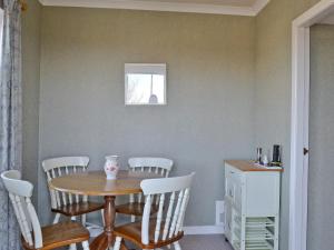 a dining room with a table and white chairs at Belloch Cottage in Glenbarr