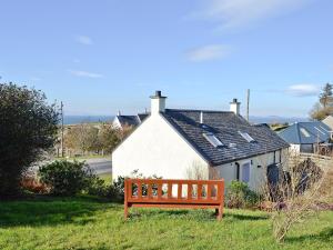 a wooden bench sitting in front of a house at Belloch Cottage in Glenbarr