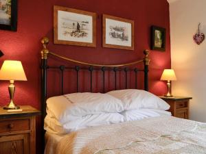una camera da letto con un letto con pareti rosse e due lampade di Tanners Cottage a Cockermouth
