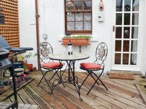 una mesa y 2 sillas en una terraza de madera en Tanners Cottage, en Cockermouth