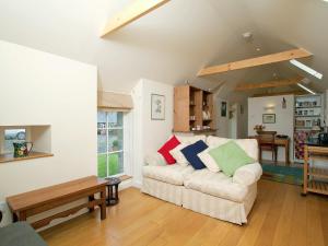 ein Wohnzimmer mit einer weißen Couch mit bunten Kissen in der Unterkunft Tullibole Castle Longhouse in Crook of Devon