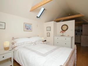 ein Schlafzimmer mit einem weißen Bett und einem Dachfenster in der Unterkunft Tullibole Castle Longhouse in Crook of Devon