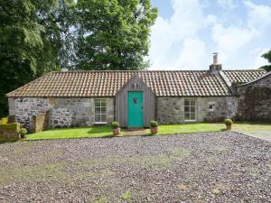 an old stone house with a green door at Tullibole Castle Longhouse in Crook of Devon