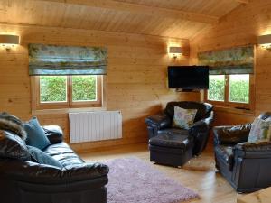 a living room with leather furniture and a flat screen tv at Ty Pren in Dyffryn
