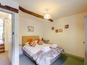 um quarto com uma cama com lençóis brancos e almofadas laranja em The Forge em Hawnby