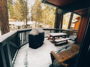 a snow covered porch with a picnic table and a bench at Remodeled Home at Snow Summit in Big Bear Lake