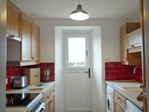 a kitchen with a white door and a window at Borrowdale Cottage in Brough