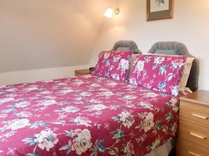 1 dormitorio con 1 cama con colcha de flores rojas en Sallys Nest - E3042 en Blyford