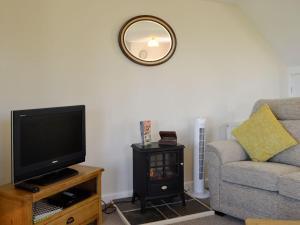 sala de estar con TV, sofá y espejo en Sallys Nest - E3042 en Blyford