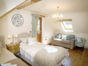 a bedroom with two beds and a chair and a chandelier at The Old Stables in Crynant