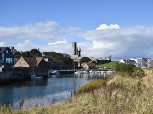 a river with boats in a town with a castle at St Andrews Hideaway in St. Andrews