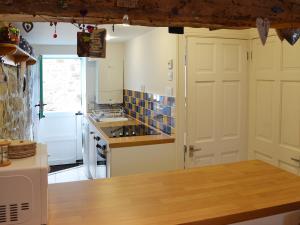 a kitchen with white cabinets and a wooden counter top at Driftwood in St Ives